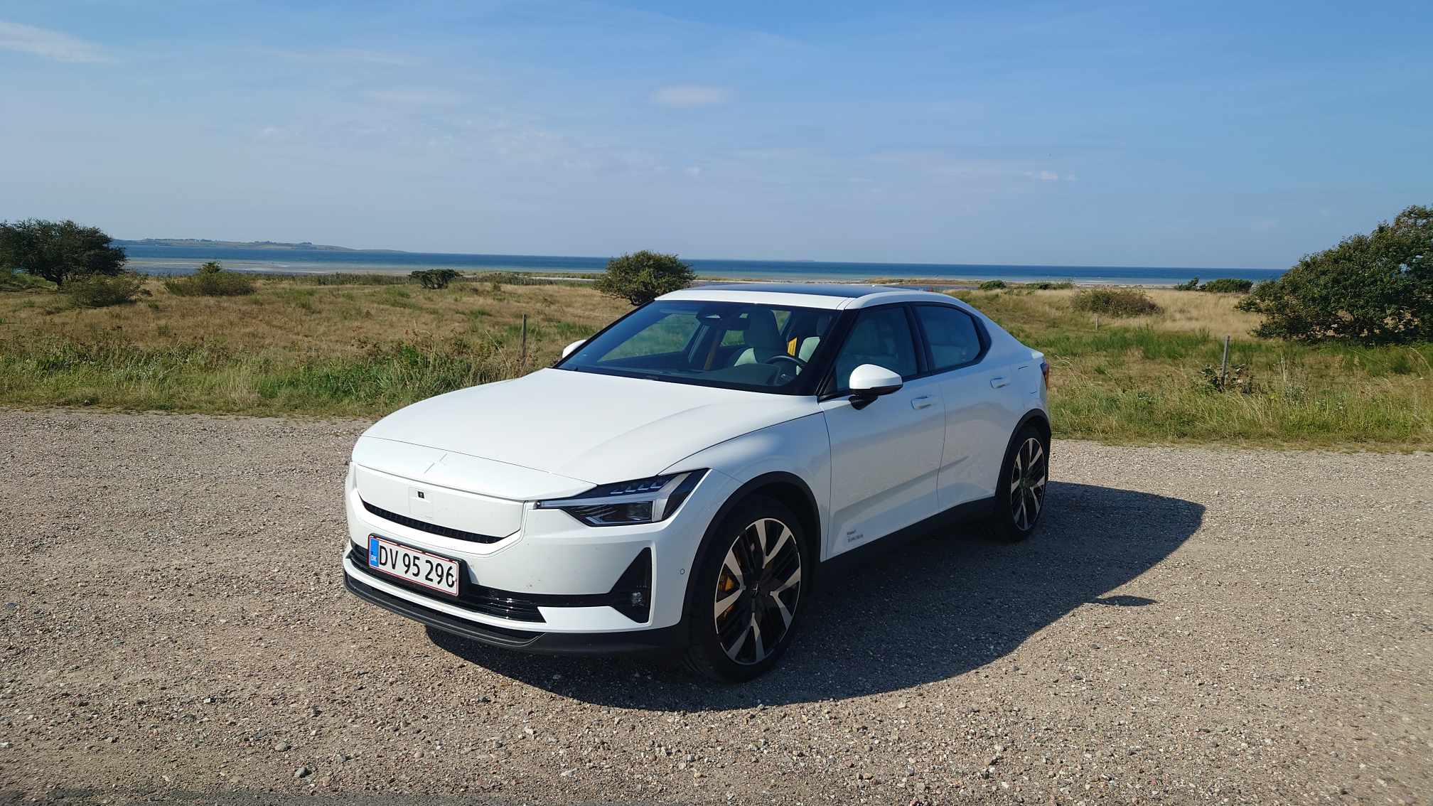 Hvid Polestar 2 front og side med natur og havet i baggrunden